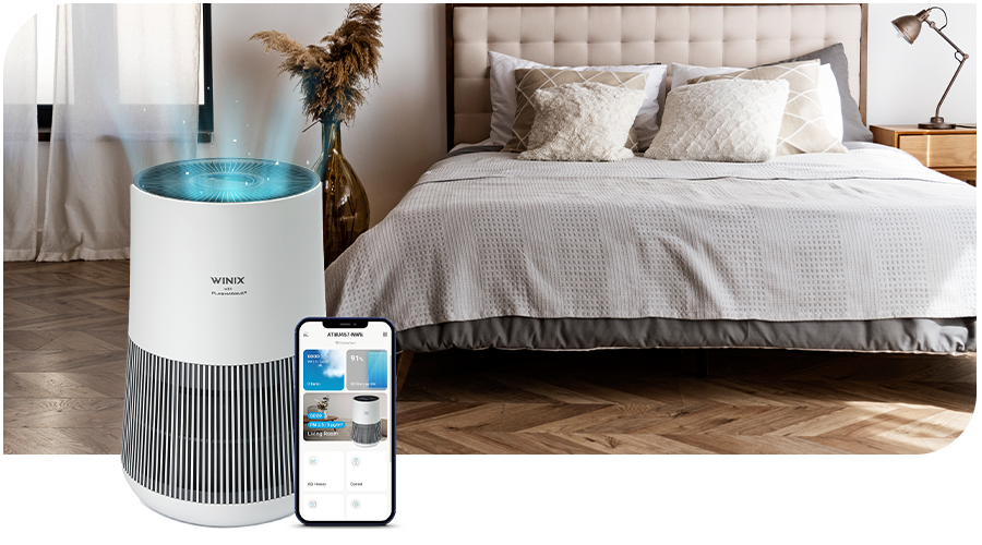 Purificateur d’air WINIX avec un smartphone devant un lit